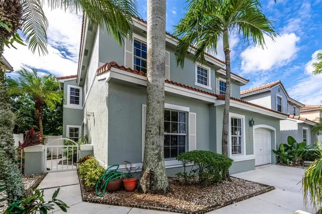front view of a house with a potted plants and a palm tree