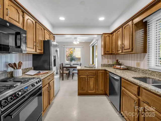 a kitchen with stainless steel appliances granite countertop a stove a sink dishwasher and a microwave oven with large cabinets