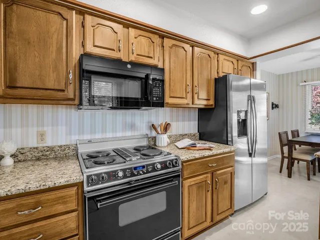 a kitchen with stainless steel appliances granite countertop a stove a refrigerator and a microwave