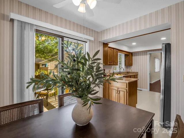 a kitchen with stainless steel appliances granite countertop a stove a refrigerator a sink a dining table and chairs with wooden floor