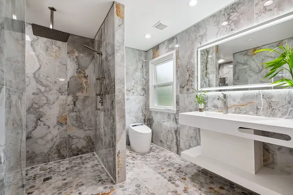 a bathroom with a granite countertop sink toilet a mirror and shower