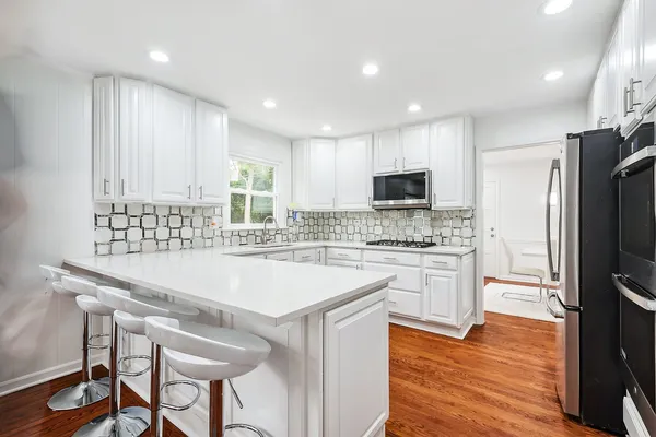 a kitchen with stainless steel appliances granite countertop a white cabinets and wooden floor