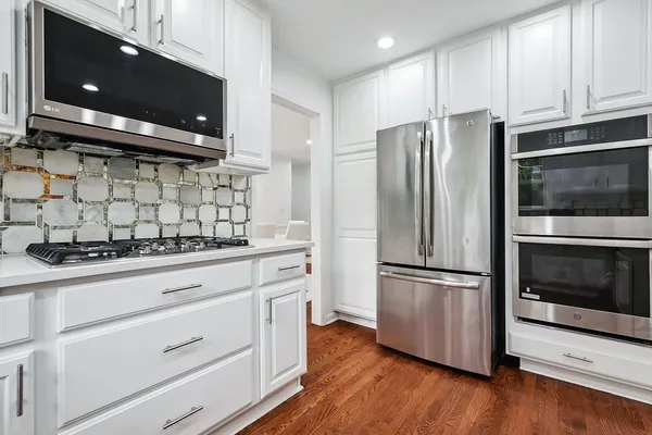 a kitchen with granite countertop white cabinets and stainless steel appliances