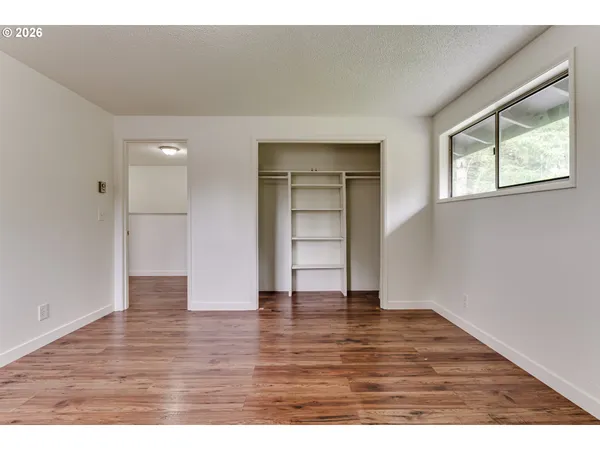 an empty room with wooden floor cabinet and windows