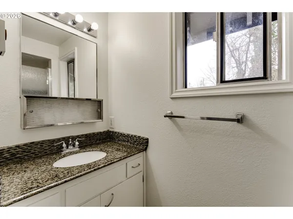 a bathroom with a granite countertop sink and a mirror