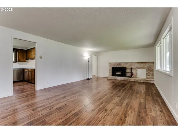 a view of empty room with wooden floor and fireplace