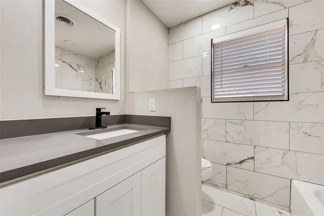 a bathroom with a granite countertop sink a vanity and mirror