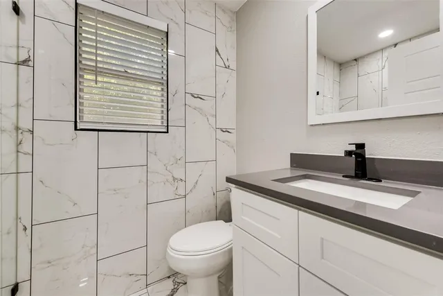 a bathroom with a granite countertop sink toilet and mirror