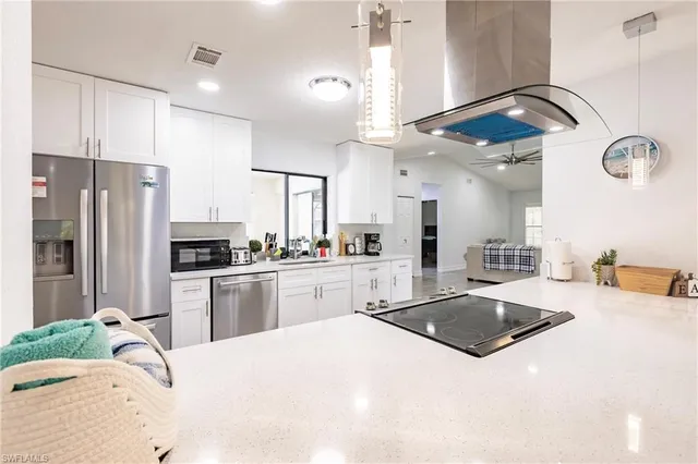 a kitchen with stainless steel appliances kitchen island granite countertop a sink a stove a refrigerator and island with wooden floor