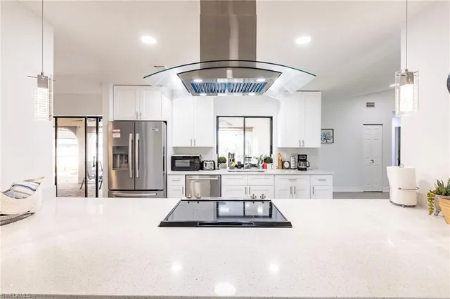 a living room with stainless steel appliances kitchen island furniture and a chandelier