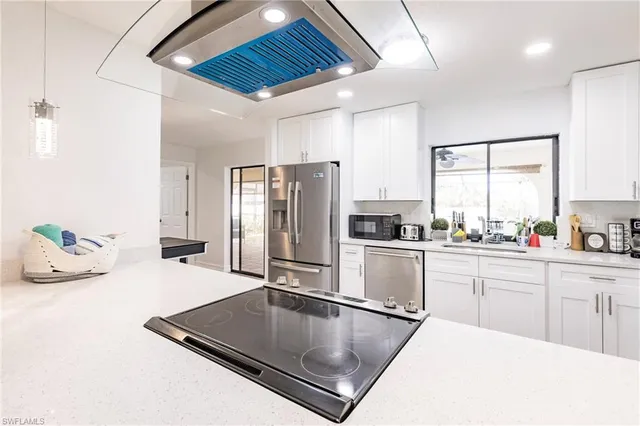 a kitchen with stainless steel appliances granite countertop a refrigerator a sink and white cabinets