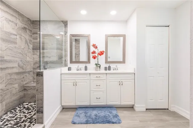 a spacious bathroom with a double vanity sink a mirror and a shower