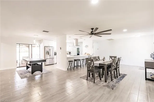 a dining room with wooden floor a chandelier a glass table and chairs