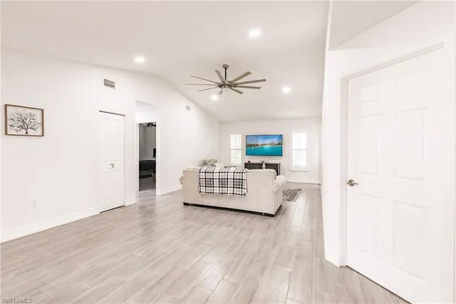 a view of an empty room with kitchen and window