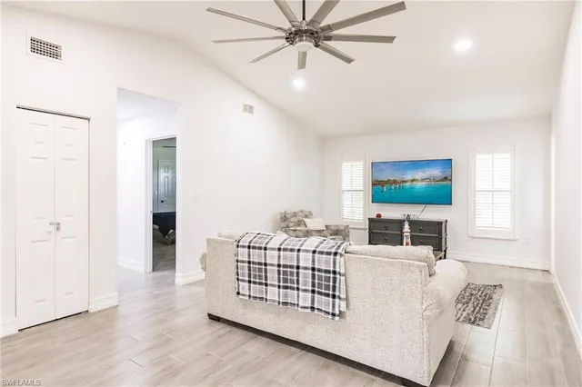 a living room with a flat screen tv furniture and a ceiling fan