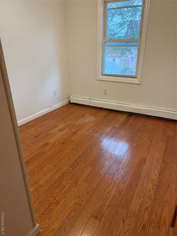 an empty room with wooden floor and window