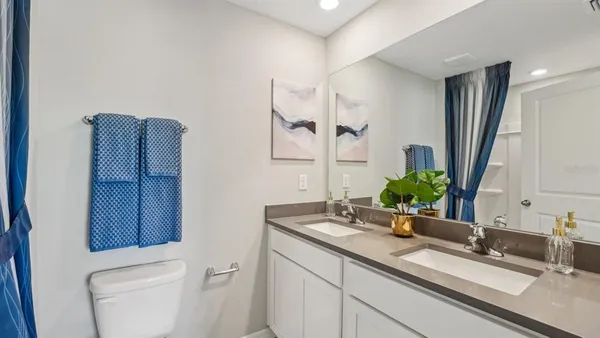 a bathroom with a granite countertop toilet sink and mirror