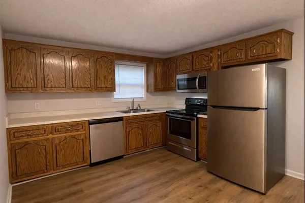 a kitchen with granite countertop stainless steel appliances a refrigerator a sink and cabinets