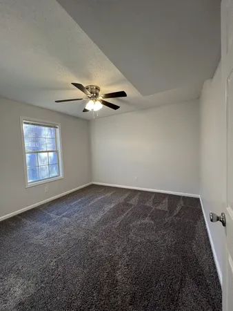 an empty room with windows and fan