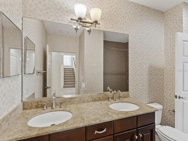 a bathroom with a granite countertop sink a toilet and a mirror