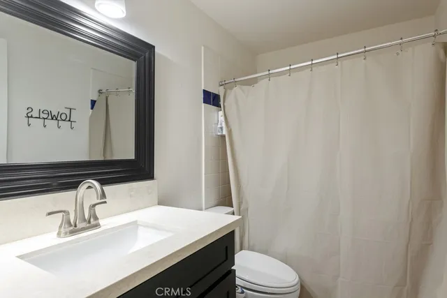 a bathroom with a sink a toilet a mirror and shower curtain