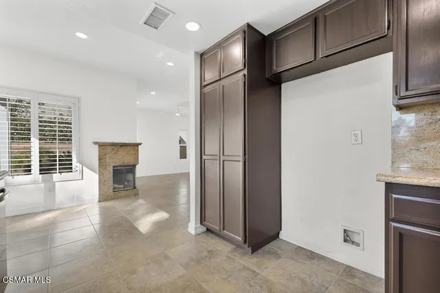 a view of a refrigerator in kitchen and an empty room with windows