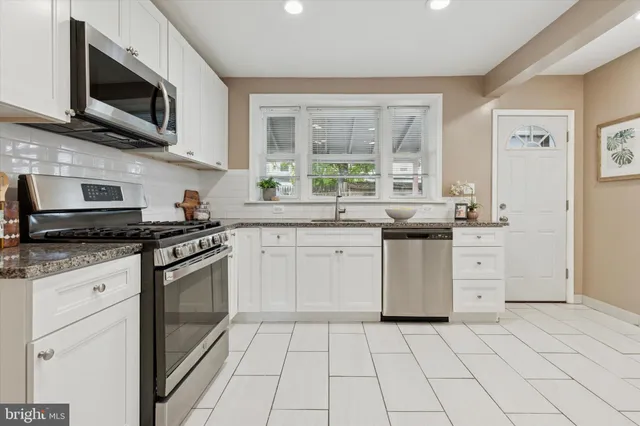 a kitchen with stainless steel appliances granite countertop a stove a sink and a microwave