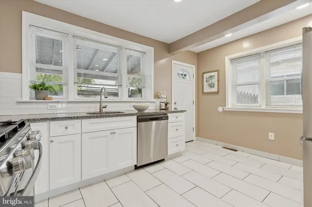 a kitchen with granite countertop a sink white cabinets and a window
