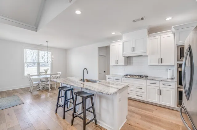 a kitchen with stainless steel appliances granite countertop a kitchen island hardwood floor and a sink