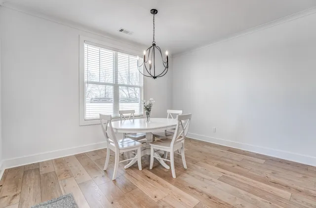 a view of a dining room with furniture a chandelier and wooden floor