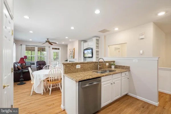 a dining hall with stainless steel appliances granite countertop a sink and dishwasher with wooden floor