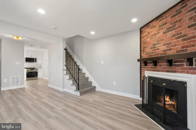 a view of an empty room with wooden floor fireplace and a window