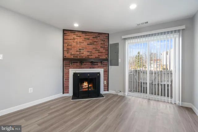 a view of an empty room with wooden floor and a fireplace