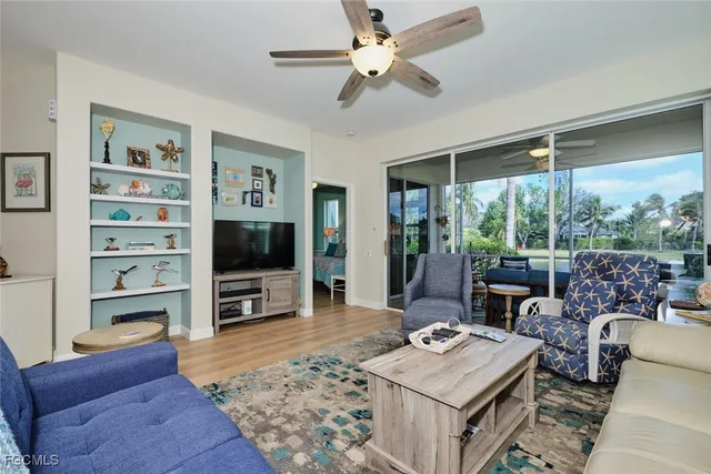 a living room with furniture a flat screen tv and a floor to ceiling window