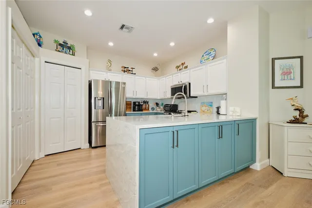 a kitchen with stainless steel appliances kitchen island granite countertop a refrigerator and a sink