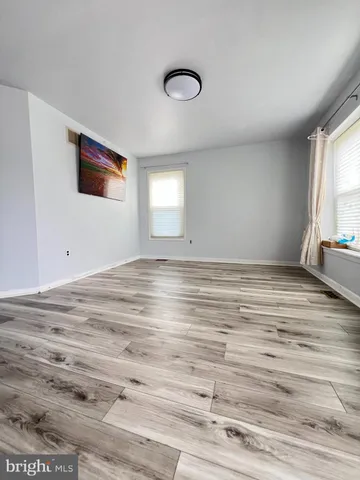 a view of empty room with window and wooden floor
