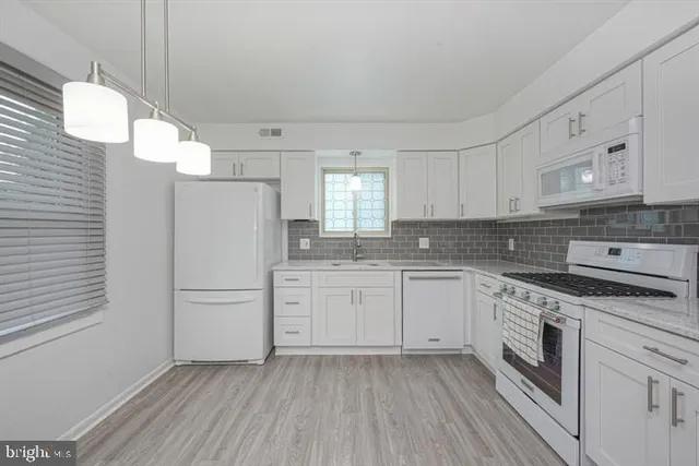 a kitchen with granite countertop white cabinets and white appliances