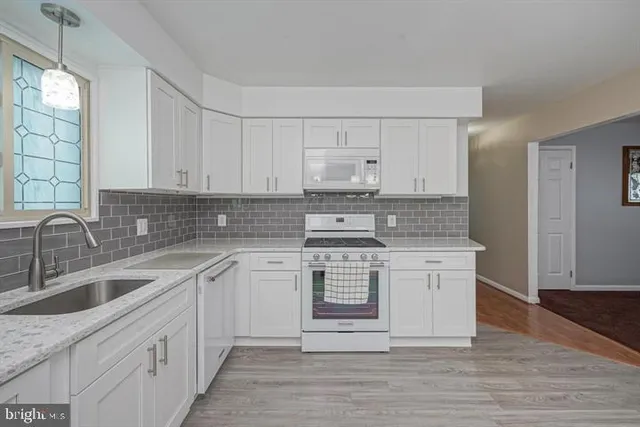 a kitchen with stainless steel appliances granite countertop a sink stove and white cabinets
