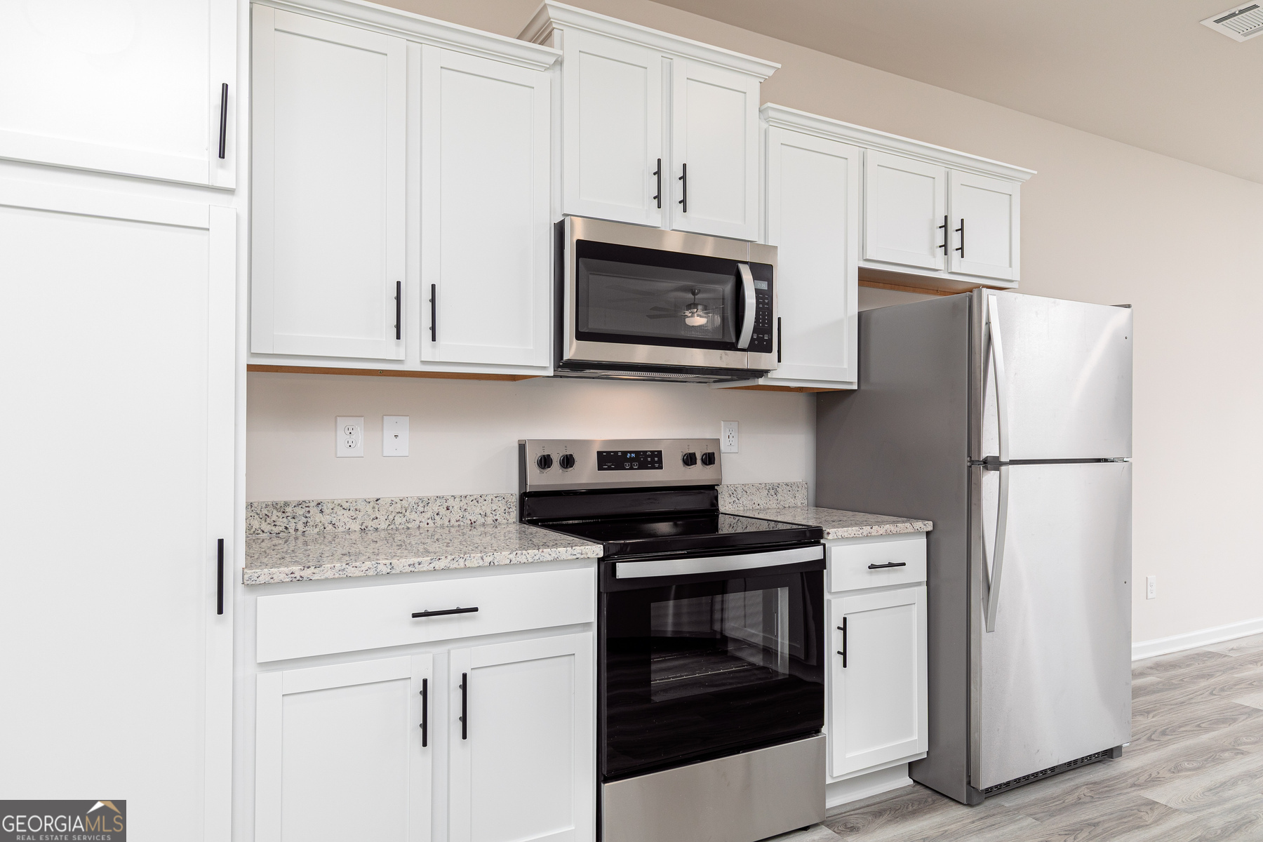 516 Plant Road Conyers, GA 30013 - Photo 5 of 11 a kitchen with stainless steel appliances granite countertop white cabinets a refrigerator and a stove a refrigerator with wooden floors