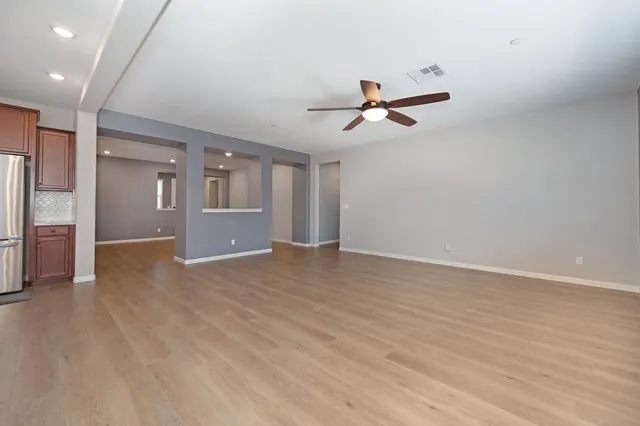a view of empty room with wooden floor and ceiling fan