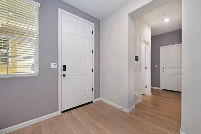 a view of an empty room with wooden floor and a bathroom