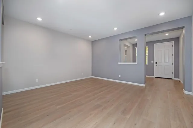 a view of an empty room with wooden floor and a bathroom
