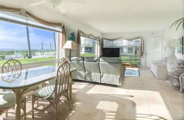 a view of a dining room with furniture a chandelier and large windows