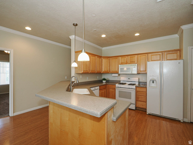 1138 Meadow Fork Road, Unit 7 Provo, UT 84606 - Photo 13 of 27 Kitchen featuring wood-finish flooring, light wood cabinetry, white appliances, and a breakfast bar with pendant lighting