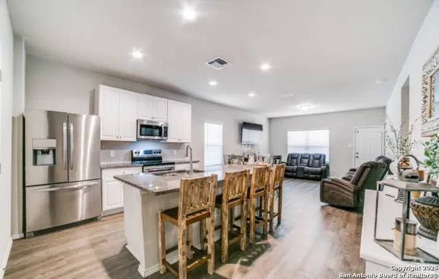 a kitchen with granite countertop a sink a counter top space stainless steel appliances and cabinets