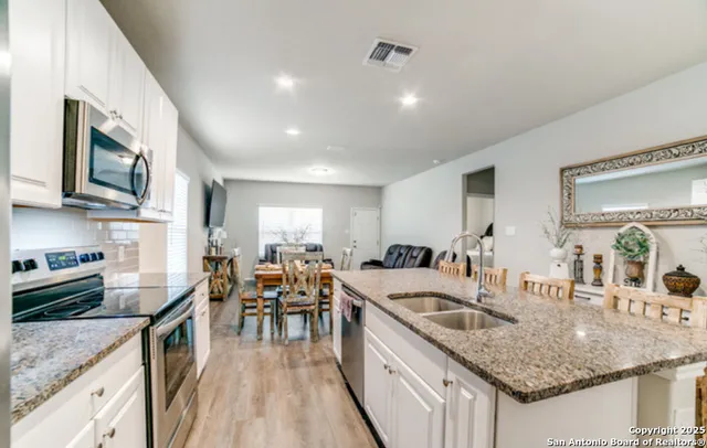 a kitchen with granite countertop kitchen island stainless steel appliances a stove a table and chairs