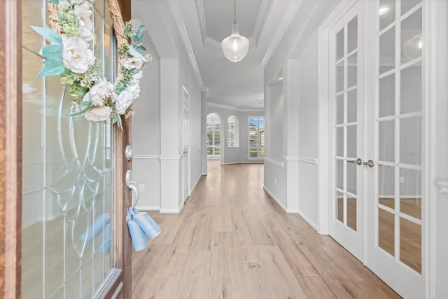 a view of an empty room with wooden floor and a chandelier