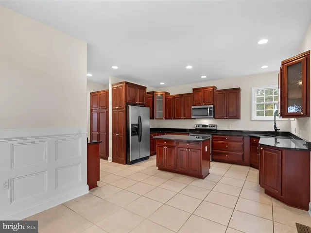 a kitchen with stainless steel appliances granite countertop wooden cabinets a stove a sink and a refrigerator