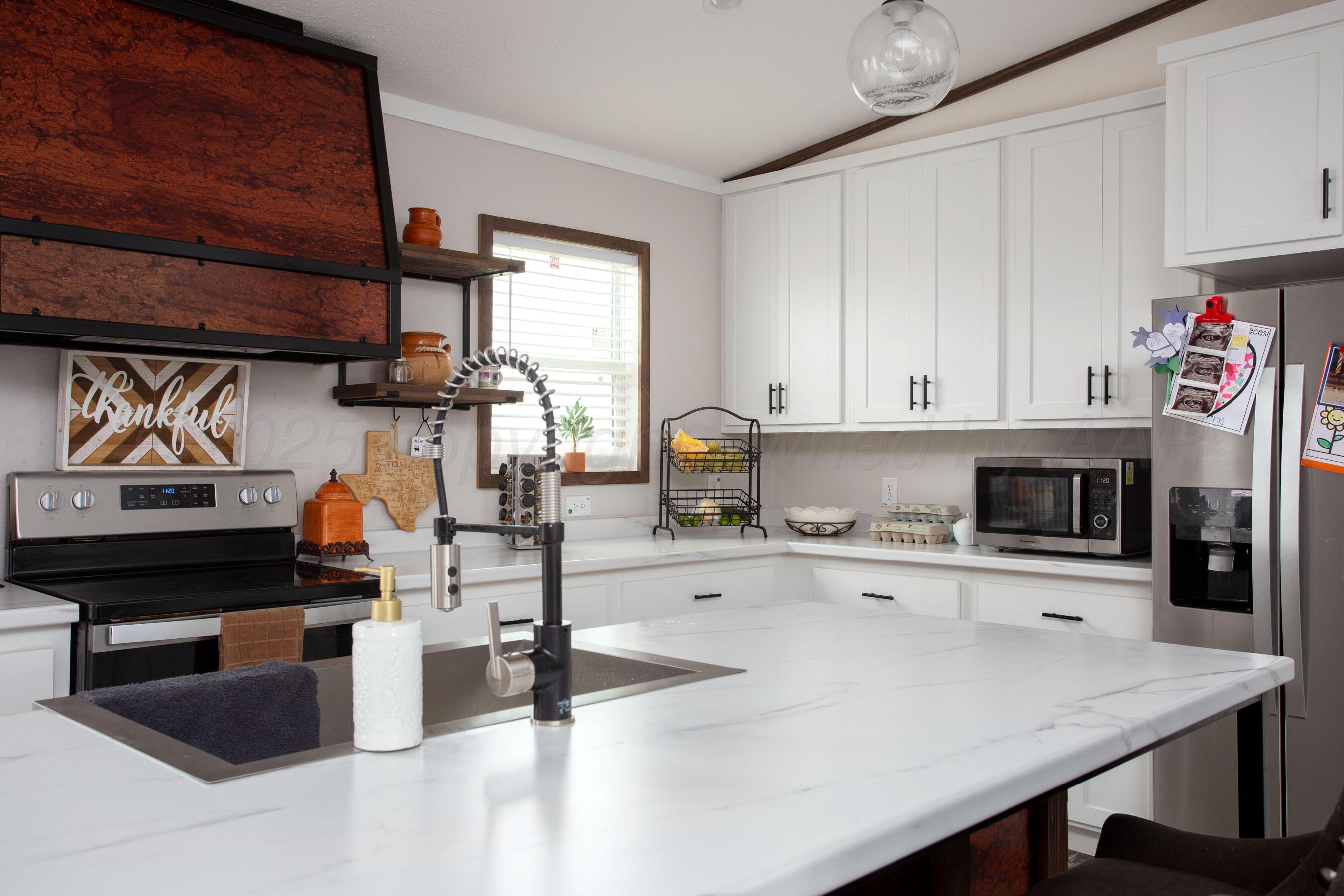 6300 Voorhees Road Amarillo, TX 79119 - Photo 7 of 27 a kitchen with a stove a refrigerator and a sink with cabinets