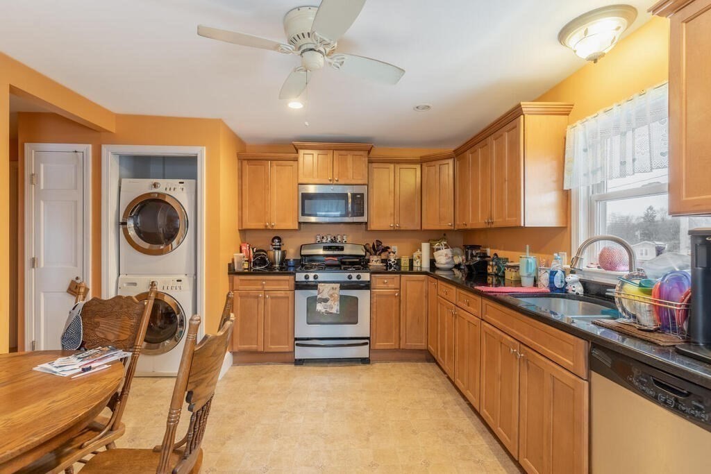 20 Washington Street Danvers, MA 01923 - Photo 18 of 39 a kitchen with stainless steel appliances granite countertop a sink a stove top oven a chimney cabinets and a dining table